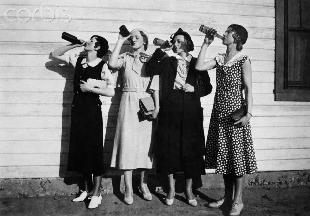 Flapper women drink in unison, ca. 1925.
